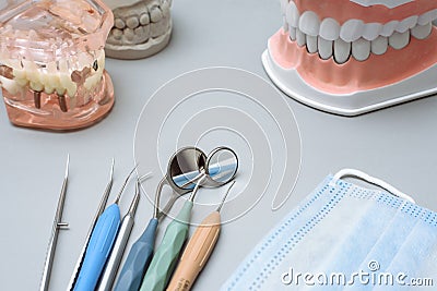 Dentist tools, medical mask and artificial jaws on a blue background Stock Photo