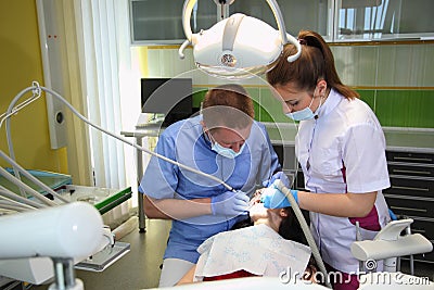 Dentist treating a patient`s teeth with dental tools in dental clinic. Dentistry. Editorial Stock Photo