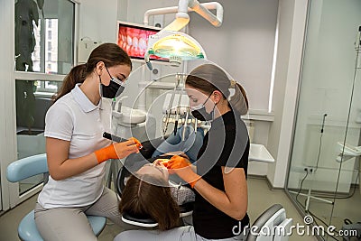 Dentist uses professional equipment to whiten the patient`s teeth in the clinic Stock Photo