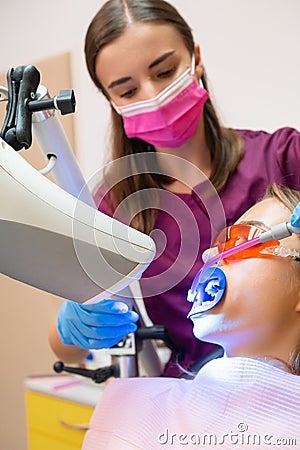 A dentist uses a saliva ejector while conducting a professional teeth whitening procedure Stock Photo