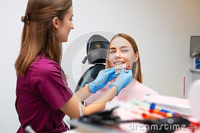 Dentist uses shades of tone for whitening of teeth and perfect woman smile for patient. Stock Photo