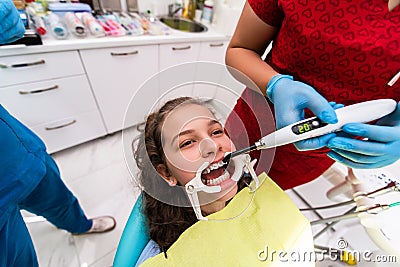 The dentist uses an ultraviolet lamp while fitting the girl with braces Stock Photo