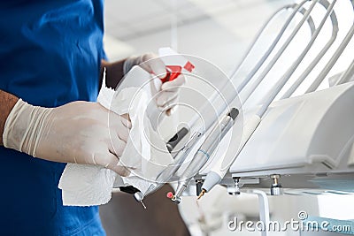 Dentist using antiseptic sanitizer, while cleaning stomatology equipment Stock Photo