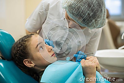 Dentist woman doing teeth checkup of little girl looking with fear sitting in a dental chair in clinic Stock Photo