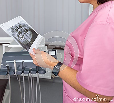 Dentist woman in pink uniform looking at roentgen of human jaw Stock Photo