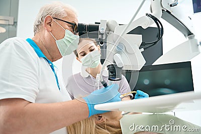 Dentist working with the patient and microscope Stock Photo