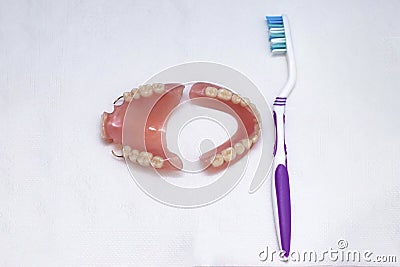 Dentures lie on a white background and a toothbrush, upper and lower jaw, top view. Dental prosthetics, care for removable Stock Photo