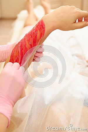 depilation and beauty concept - procedure of hair removing on hand woman with sugar paste or wax honey and pink gloves Stock Photo