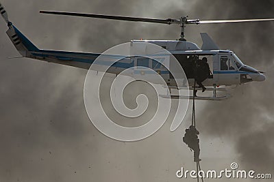 Deploying troops from a military helicopter using fast-roping technique. Special force landing Stock Photo