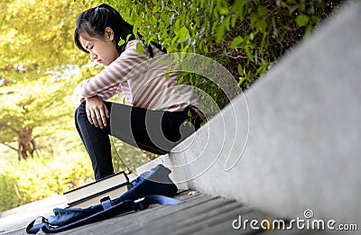 Depressed asian child girl disappointed with her exam at primary school,female student sitting alone,sad schoolgirl feel stressed, Stock Photo