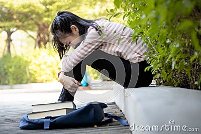Depressed asian child girl student failed important test,female student sit hugs her knees up to the chest and crying alone,sad Stock Photo