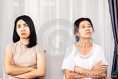 Depressed Asian mother and daughter sitting at sofa angry, quarrel, ignoring each other , serious relationship in family concept Stock Photo