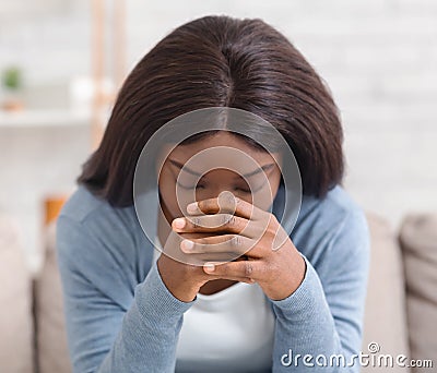Depressed black woman sitting alone at home, feeling desperate Stock Photo