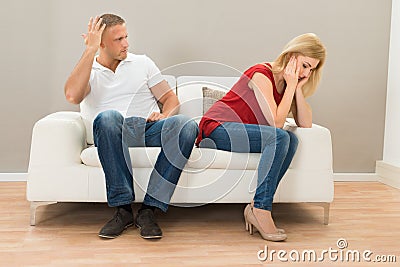 Depressed couple sitting on sofa Stock Photo