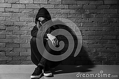 Depressed female junkie near brick wall. Concept of addiction Stock Photo