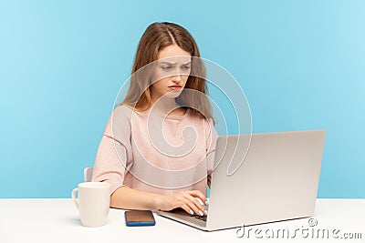 Depressed gloomy businesswoman in casual clothes typing on laptop, reading bad news with frustrated upset expression Stock Photo