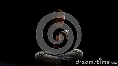 Depressed lady sitting in darkness hugging teddy bear, obstetric violence victim Stock Photo