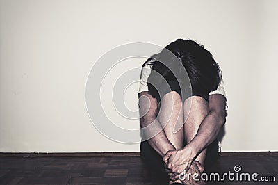 Depressed and lonely girl abused as young sitting alone in her room on the floor feeling miserable and anxiety cry over her life, Stock Photo