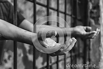 A depressed man in handcuffs behind bars. A depressed arrested male offender is jailed. Stock Photo