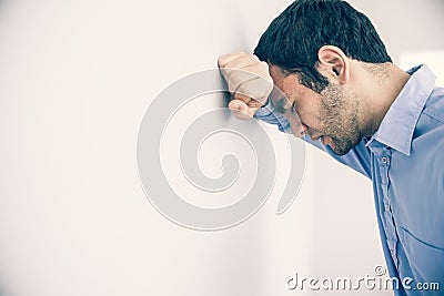 Depressed man leaning his head against a wall Stock Photo