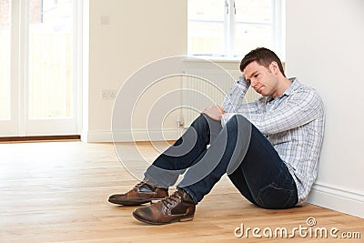 Depressed Man Sitting In Empty Room Of Repossessed House Stock Photo