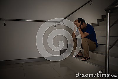 Depressed man sitting on stair of residence building. Sad man, Cry, drama, lonely and unhappy concept Stock Photo