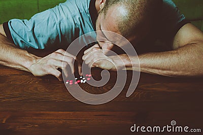 Depressed man suffering from suicidal depression want to commit suicide by taking strong medicament drugs and pills and he is cove Stock Photo