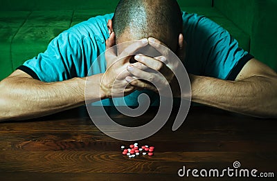 Depressed man suffering from suicidal depression want to commit suicide by taking strong medicament drugs and pills while he is si Stock Photo