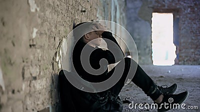 Depressed teen hiding from bullying in abandoned house, difficult adolescence Stock Photo