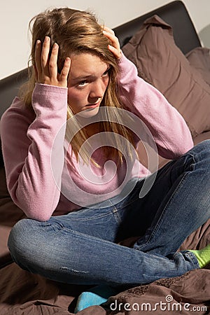 Depressed Teenage Girl Sitting In Bedroom At Home Stock Photo