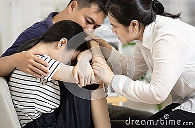 Depressed teenager girl with depressive symptoms,depression disease,feels sad crying,asian mom and dad hugging embracing daughter Stock Photo