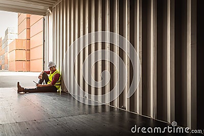 Depressed and tried foreman sitting in container shipping box Stock Photo