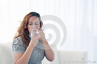 Woman drinks a pill from pain Stock Photo