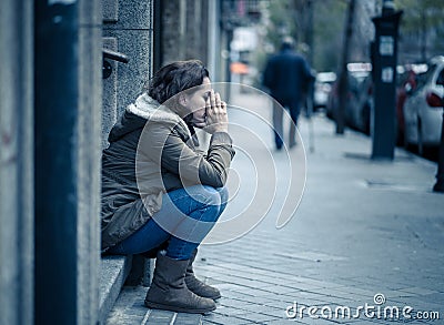 Depressed woman sitting on urban city street overwhelmed and hop Stock Photo