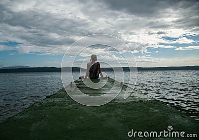 Depressed woman.Young girl depression,stress and problems,pain,female depressed.Young woman sitting on pier looking over horizon Stock Photo