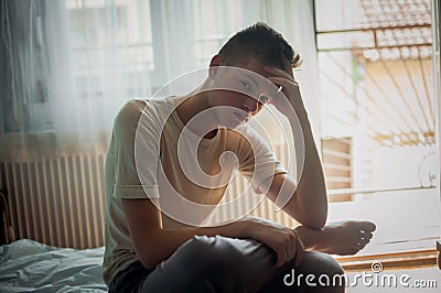 depressed young boy is sitting in bed Stock Photo