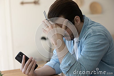 Unhappy man distressed with problems paying online on cell Stock Photo