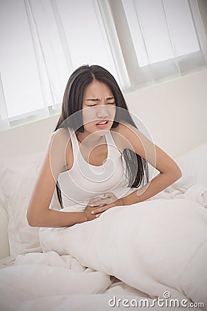 Depressed young woman with terrible stomach ache touching het tummy Stock Photo