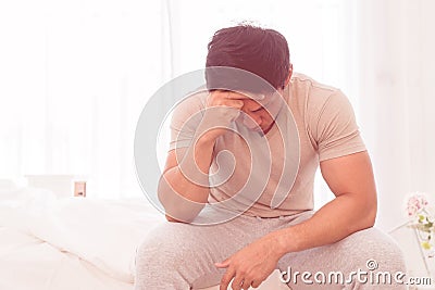 Depressing man is siting on bed with headache Stock Photo