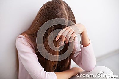 Depression in adolescence - young teenager girl sitting by wall Stock Photo