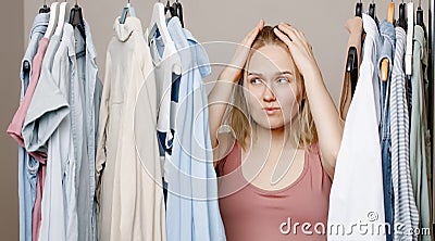 Depression a woman holds her head with her hands, standing near a closet full of clothes, facing a difficult choice of Stock Photo