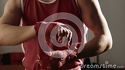 Der junge Boxer zieht roten Verband auf Händen und Kampfhaltungen Der junge Boxer zieht roten Verband auf Händen und Kampfhaltungen