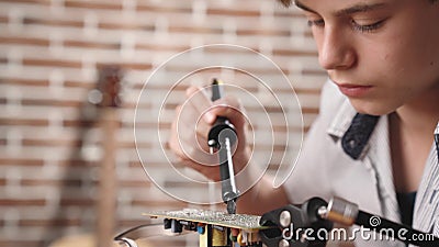 Der Junge konstruiert eine elektronische Robotermodell- und -lötmittelLeiterplatte mit Lötkolben stock footage Der Junge konstruiert eine elektronische Robotermodell- und -lötmittelLeiterplatte mit Lötkolben stock footage