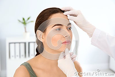 Dermatologist examining patient`s face in clinic. Stock Photo