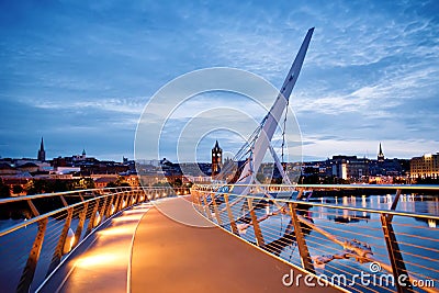 Derry, Ireland. Illuminated Peace bridge in Derry Londonderry, City of Culture, in Northern Ireland with city center at Editorial Stock Photo