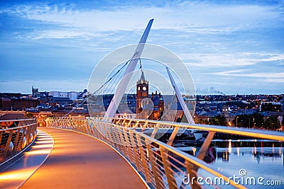 Derry, Ireland. Illuminated Peace bridge in Derry Londonderry, City of Culture, in Northern Ireland with city center at Editorial Stock Photo