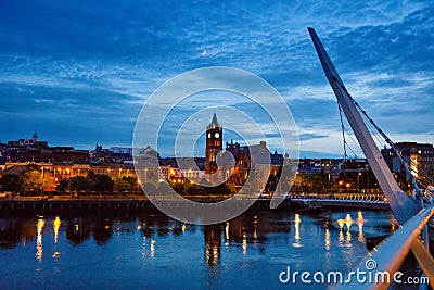 Derry, Ireland. Illuminated Peace bridge in Derry Londonderry, City of Culture, in Northern Ireland with city center at Editorial Stock Photo