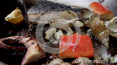 Des fruits de mer sont mélangés à une cuillère pendant faire frire dans une casserole clips vidéos Des fruits de mer sont mélangés à une cuillère pendant faire frire dans une casserole clips vidéos