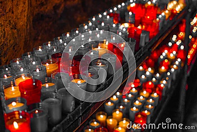 Desaturated red close up of colorful candles in a dark spiritual scene. Commemoration, funeral, memorial. Religious symbolism Stock Photo