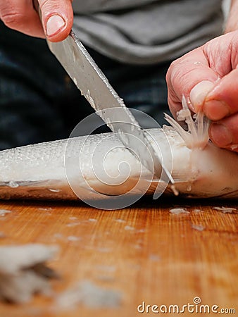 Descaling fish with sharp knife, selective focus. Sea bream on a wooden cutting board. Fishmonger at work Stock Photo